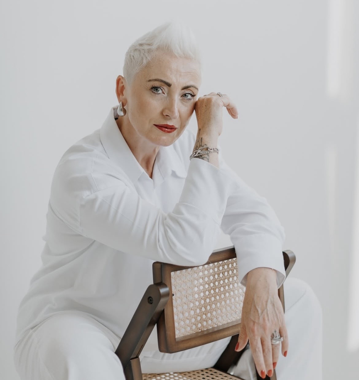 Mihaela Litschel sitz auf einem Stuhl vor einer weißen Wand.