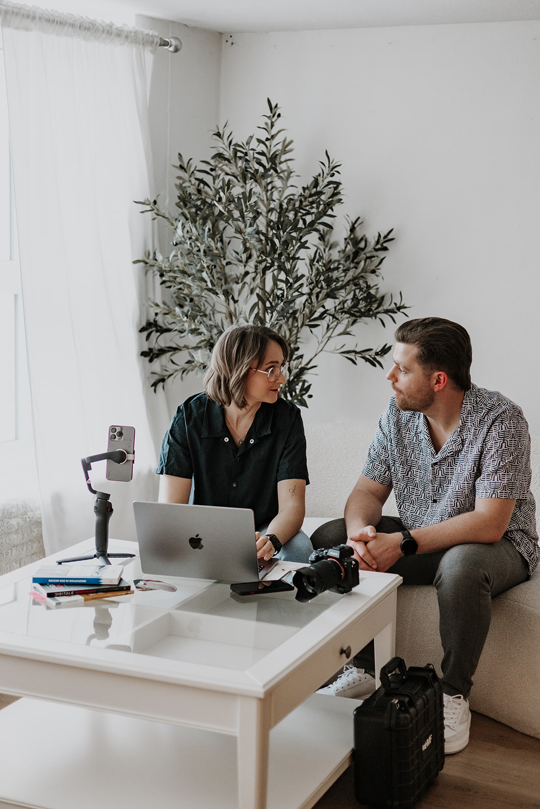 Die zwei Geschäftsführer sitzen auf einem Sofa und besprechen eine Strategie. Vor Ihnen Laptop und Equipment.