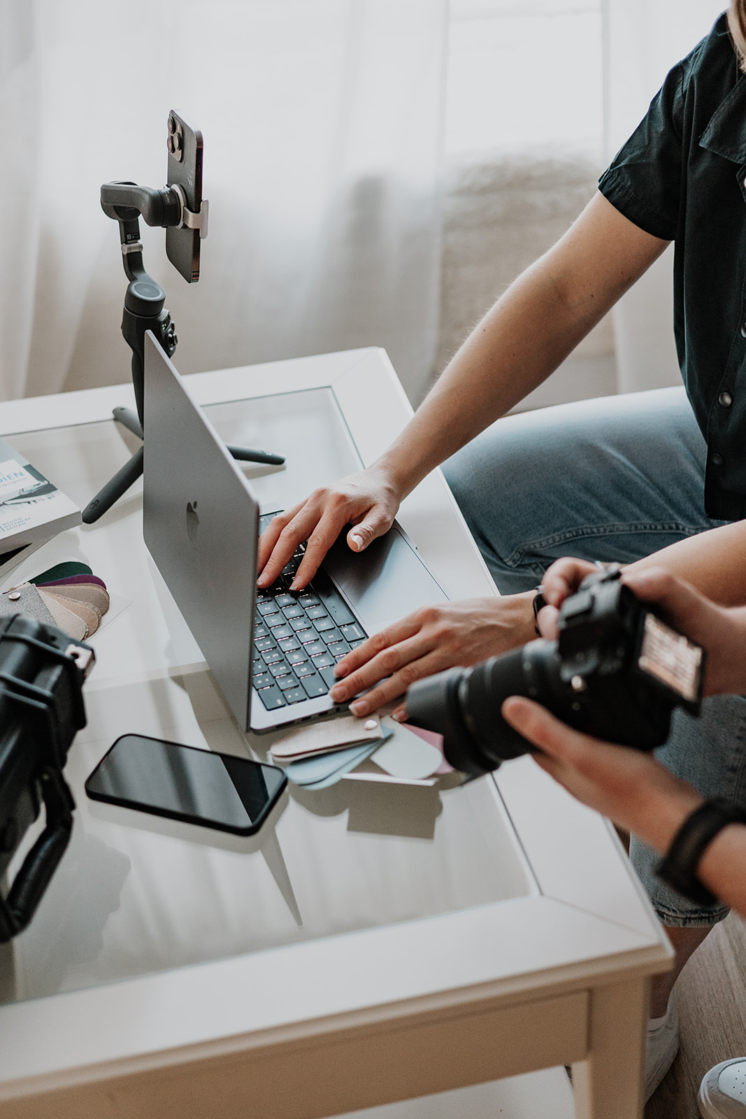 Social Media Content wird geplant und besprochen an einem Tisch mit Handy, Laptop und Kamera.