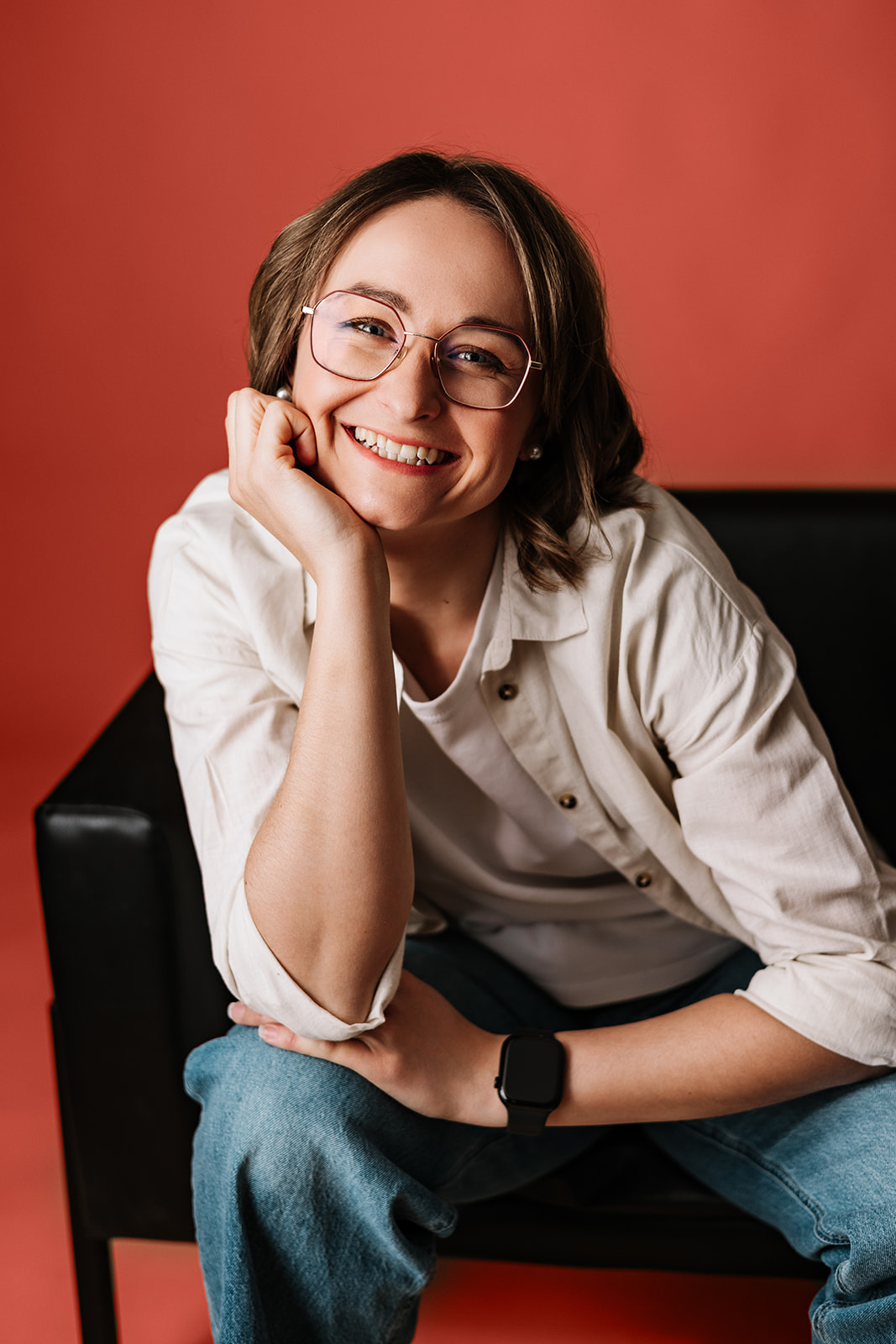 Geschäftsführerin Anni auf einem Sessel, nach vorne gelehnt und in die Kamera lachend.